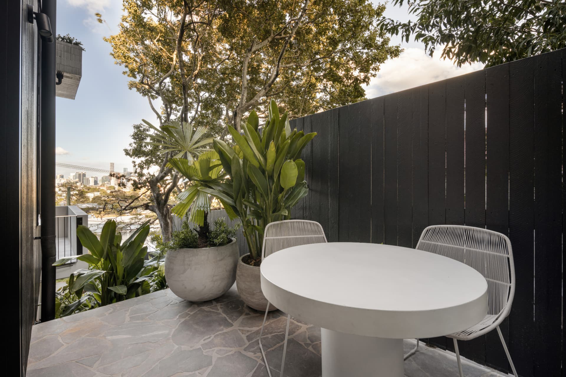 Private terrace with city glimpses, lush planting and white outdoor dining setting
