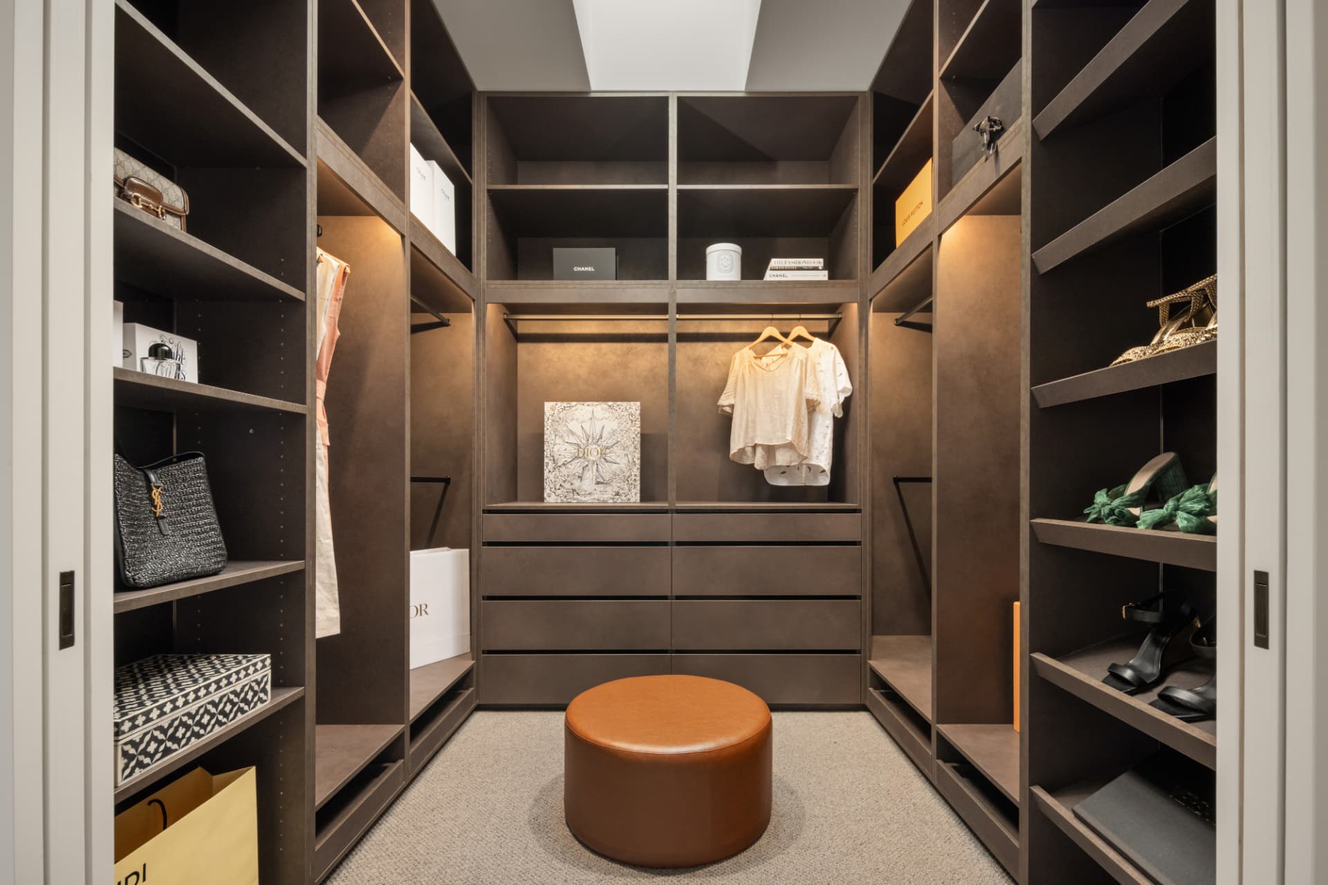 Walk-in dressing room with bronze cabinetry and skylight