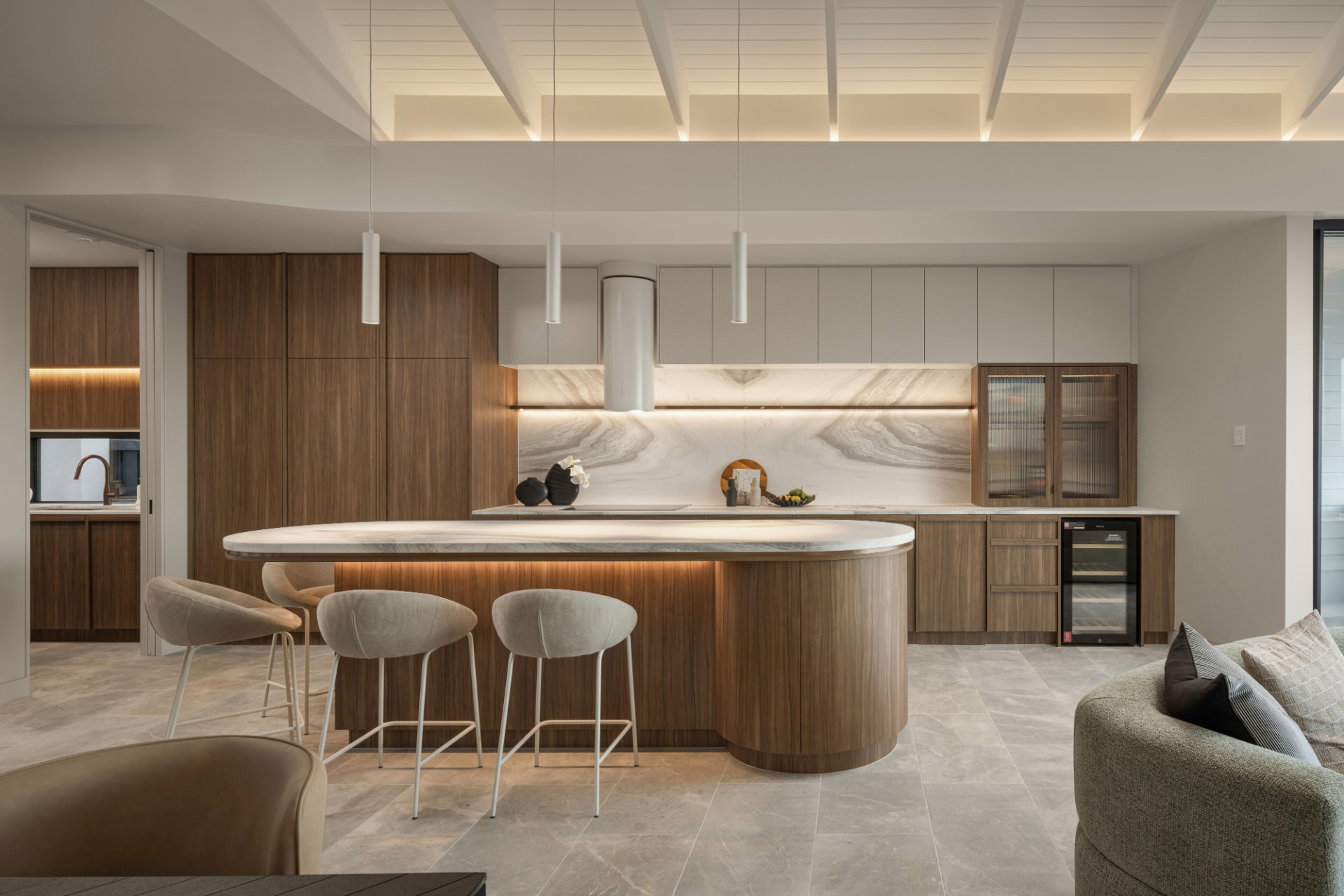 Designer kitchen with curved stone island and walnut joinery